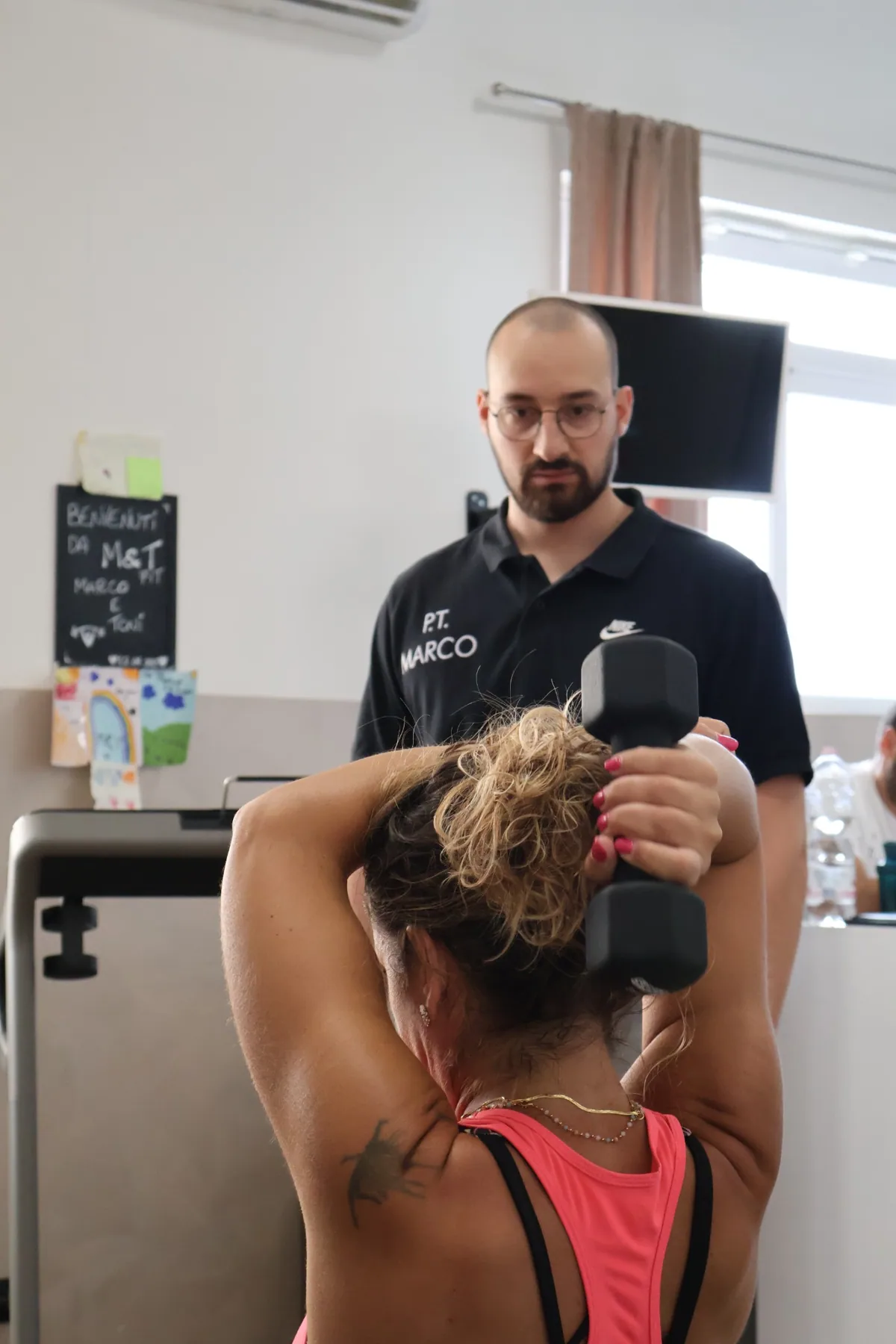 Personal trainer MeTFit segue un esercizio con manubrio